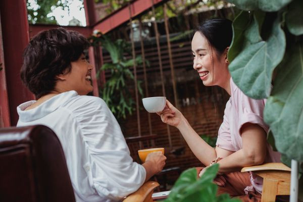 Two friends laughing naturally over coffee