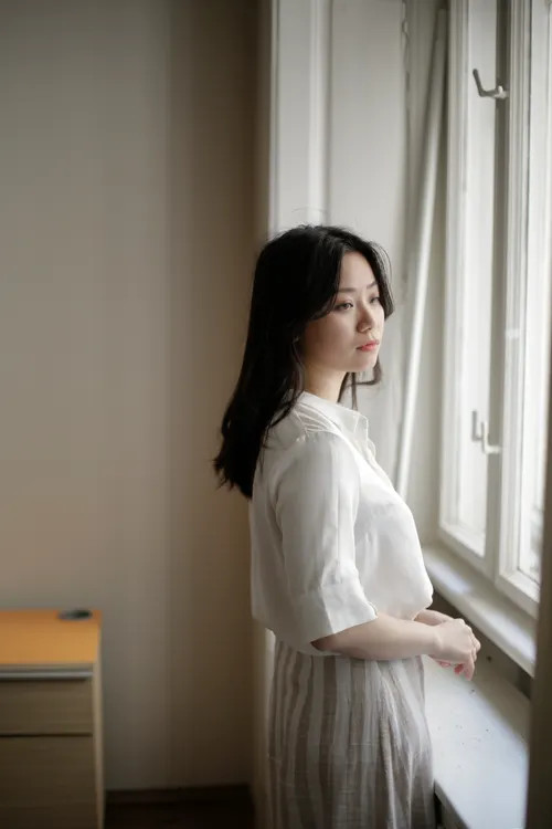 Thoughtful capable woman standing quietly by a window